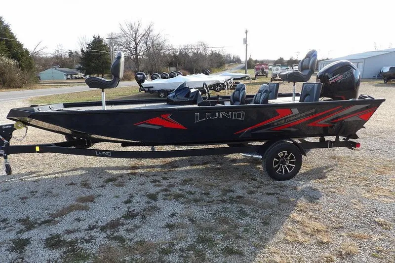 Slide: The Image of 2026 Lund 1875 Renegade fishing boat with trailer, black and red design, parked outdoors. - 4