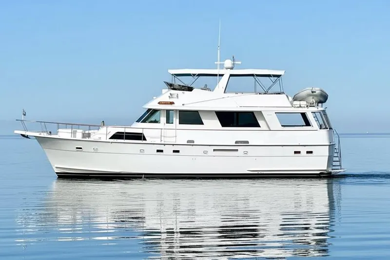 The Image of 1985 Hatteras 58 Motor Yacht on calm water, clear sky background. - 0
