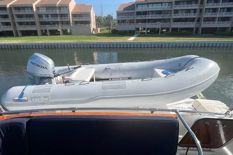 Slide: The Image of Inflatable boat with Honda motor on 1985 Hatteras 58 Motor Yacht, docked near waterfront buildings. - 13