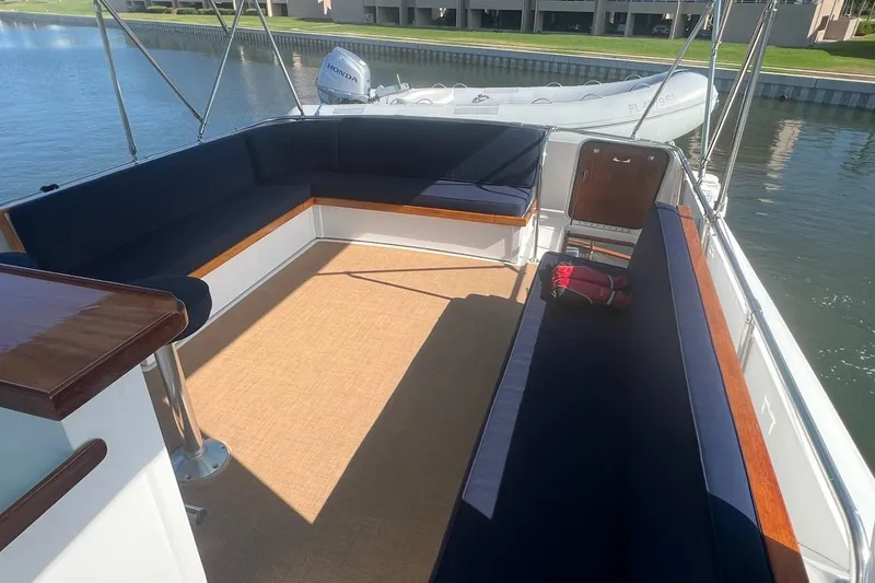 Slide: The Image of 1985 Hatteras 58 Motor Yacht deck with blue seating and a view of the water. - 14