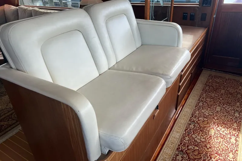 Slide: The Image of White leather seating on 1985 Hatteras 58 Motor Yacht, featuring wooden cabinetry and carpet. - 21