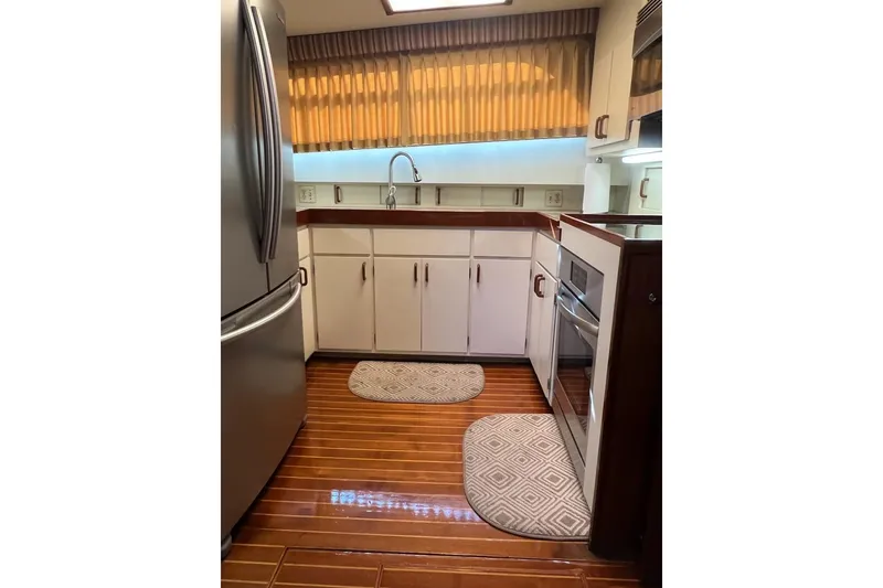 Slide: The Image of 1985 Hatteras 58 Motor Yacht kitchen with wood flooring, stainless steel appliances, and white cabinetry. - 23