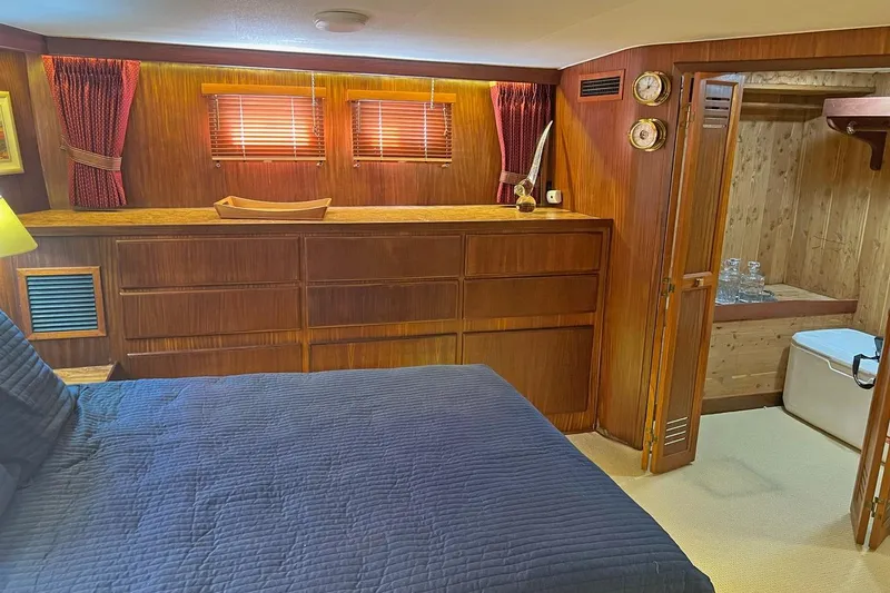 Slide: The Image of 1985 Hatteras 58 Motor Yacht interior with wood paneling, bed, and storage. - 27