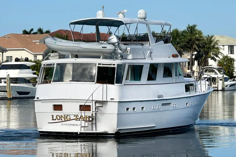 Slide: The Image of 1985 Hatteras 58 Motor Yacht docked in a scenic marina setting. - 3