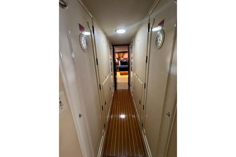 Slide: The Image of Narrow hallway inside 1985 Hatteras 58 Motor Yacht with wooden flooring and white doors. - 36