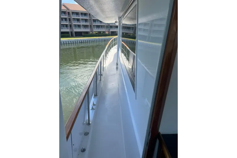 Slide: The Image of 1985 Hatteras 58 Motor Yacht side deck with railing, docked near waterfront buildings. - 42