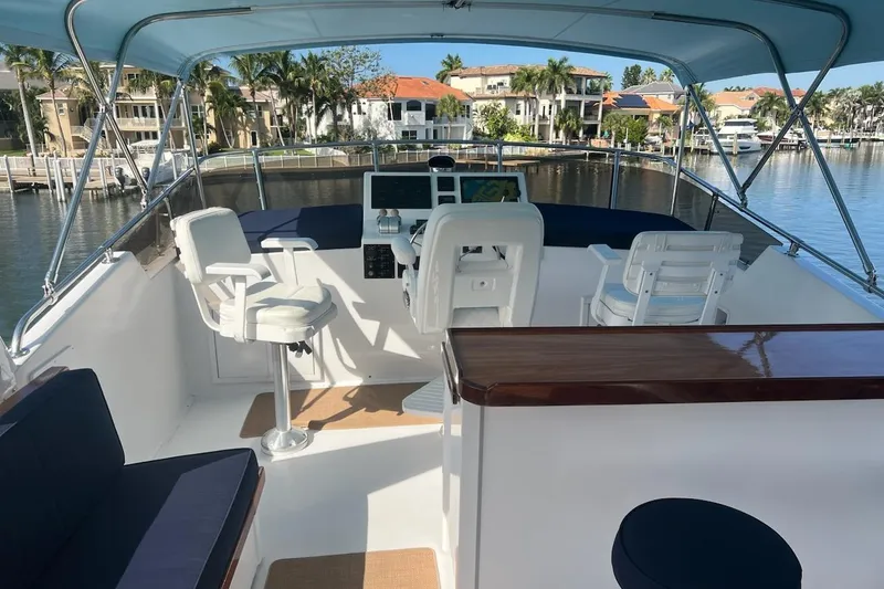 Slide: The Image of 1985 Hatteras 58 Motor Yacht helm with seating, overlooking waterfront homes and palm trees. - 7