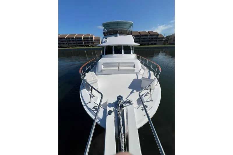 Slide: The Image of 1985 Hatteras 58 Motor Yacht on calm water, showcasing spacious deck and sleek design. - 9