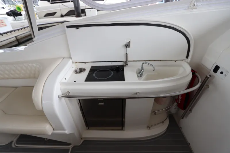 Slide: The Image of 2014 Intermarine 380 Sport yacht kitchenette with sink and stove, featuring sleek white design. - 16