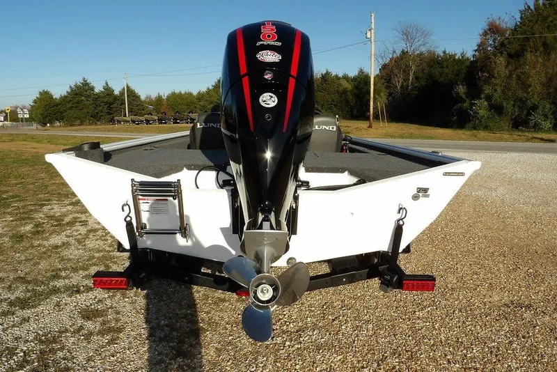 Slide: The Image of 2026 Lund 1975 Renegade boat with powerful outboard motor, parked on gravel. - 13