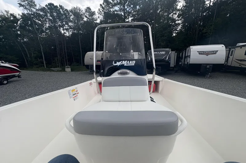 Slide: The Image of 2023 Mako Pro Skiff 17 CC boat interior with console and seating, parked outdoors. - 10