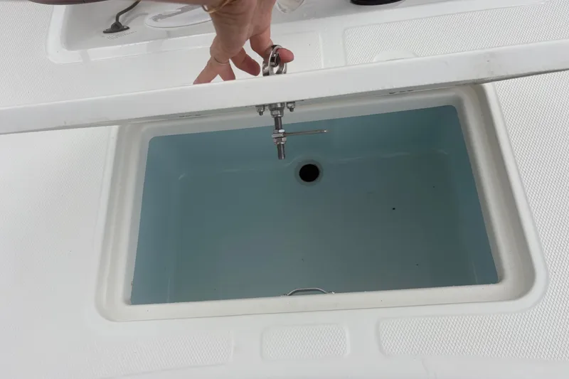 Slide: The Image of Livewell compartment on a 2023 Mako Pro Skiff 17 CC boat, open lid view. - 21
