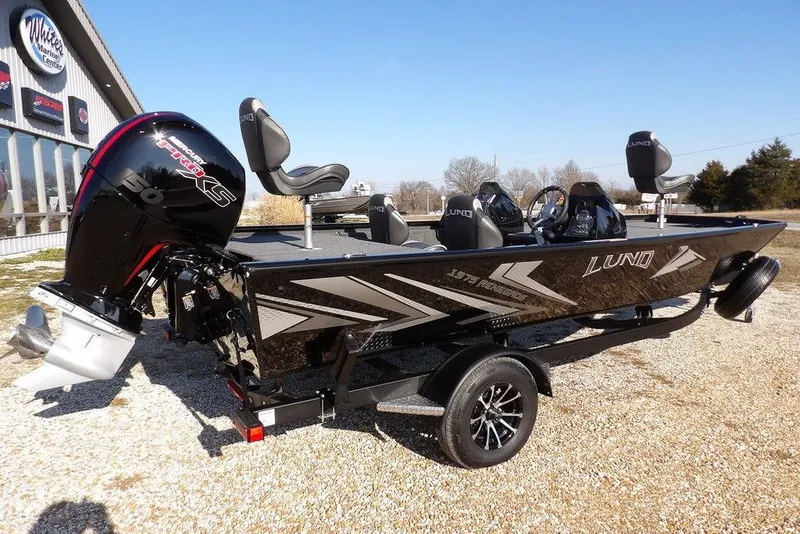 Slide: The Image of 2026 Lund 1975 Renegade boat with Mercury engine, parked outdoors on gravel. - 3