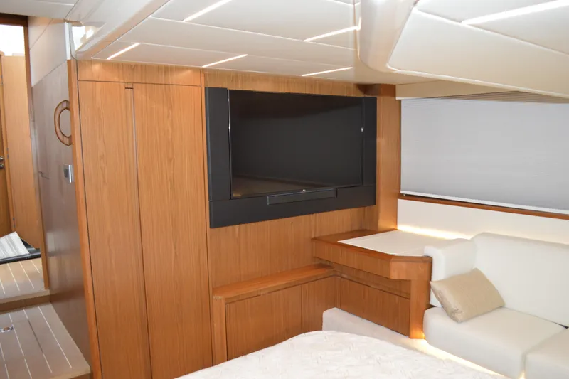 Slide: The Image of 2024 Tiara Yachts EX 60 interior with TV, wood paneling, and white seating. - 64