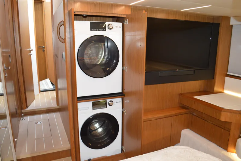 Slide: The Image of 2024 Tiara Yachts EX 60 interior with washer-dryer and TV in wooden cabinetry. - 66