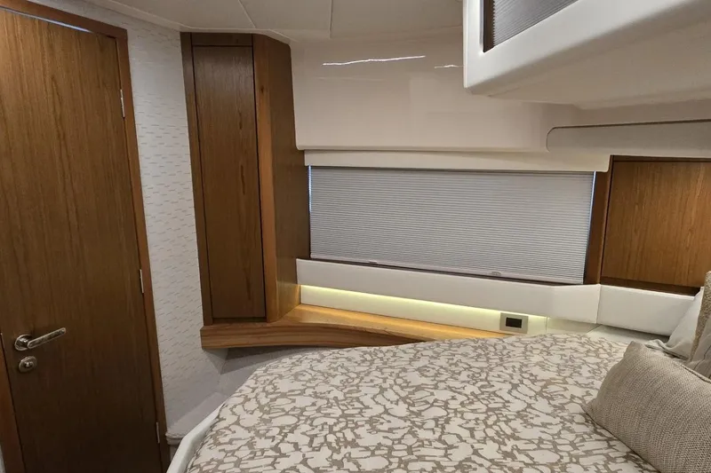 Slide: The Image of 2024 Tiara Yachts EX 60 interior cabin with modern wood accents and cozy bedding. - 75