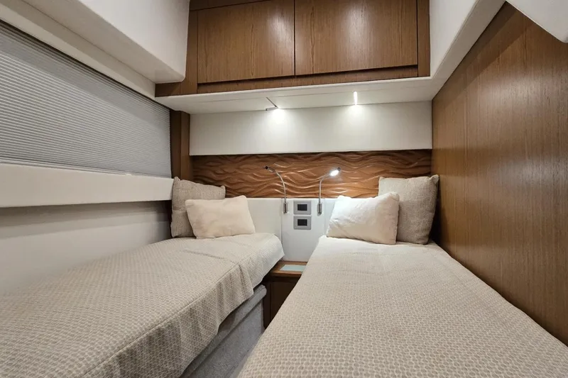 Slide: The Image of 2024 Tiara Yachts EX 60 cabin with twin beds and modern wood paneling. - 80