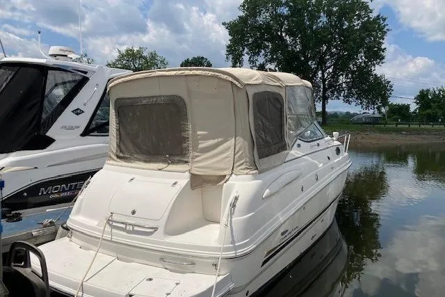 The Image of 2003 Chaparral Signature 260 boat docked on calm water, featuring a beige canopy. - 0