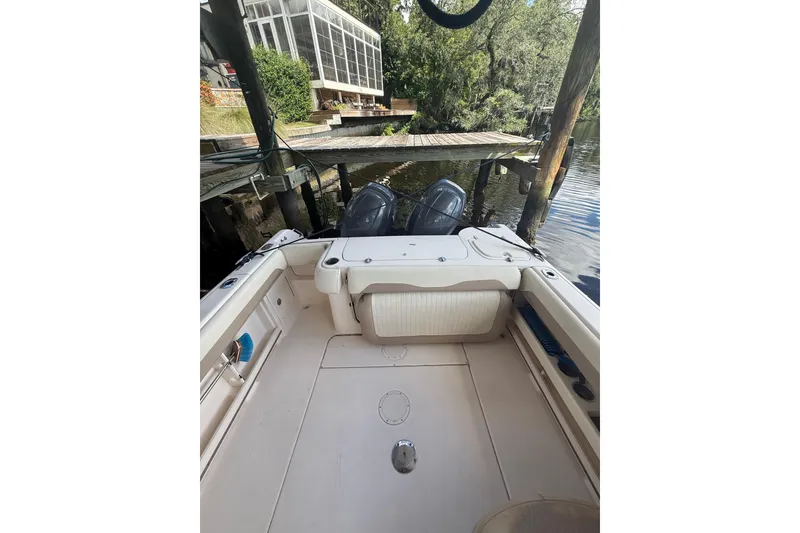 Slide: The Image of 2014 Grady-White Freedom 275 boat interior near dock, featuring dual outboard motors. - 13