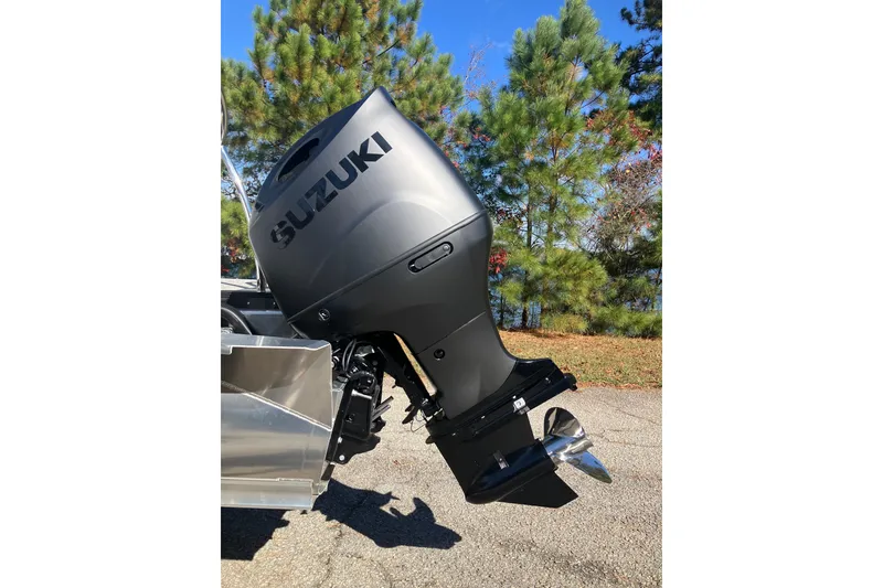 Slide: The Image of 2026 Tahoe Pontoon LTZ Quad Lounger with Suzuki outboard motor, parked outdoors. - 23