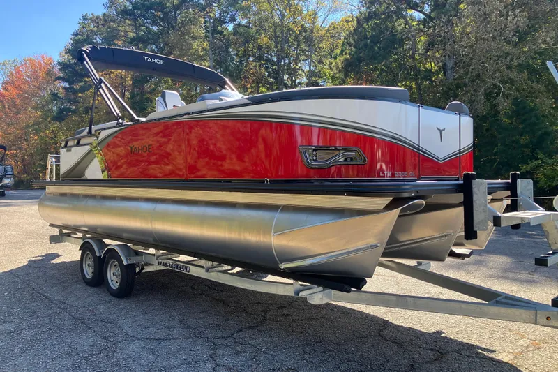 Slide: The Image of 2026 Tahoe Pontoon LTZ Quad Lounger on trailer, parked outdoors with trees in background. - 3