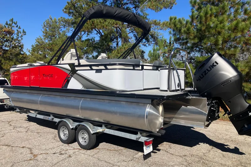 Slide: The Image of 2026 Tahoe Pontoon LTZ Quad Lounger with Suzuki engine on trailer, surrounded by trees. - 7
