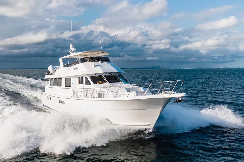 Slide: The Image of 2000 Hatteras 74 Cockpit Motor Yacht cruising on open water under cloudy skies. - 10