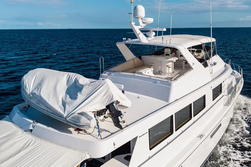Slide: The Image of Hatteras 74 Cockpit Motor Yacht 2000 cruising on open sea, featuring spacious deck and covered tender. - 22