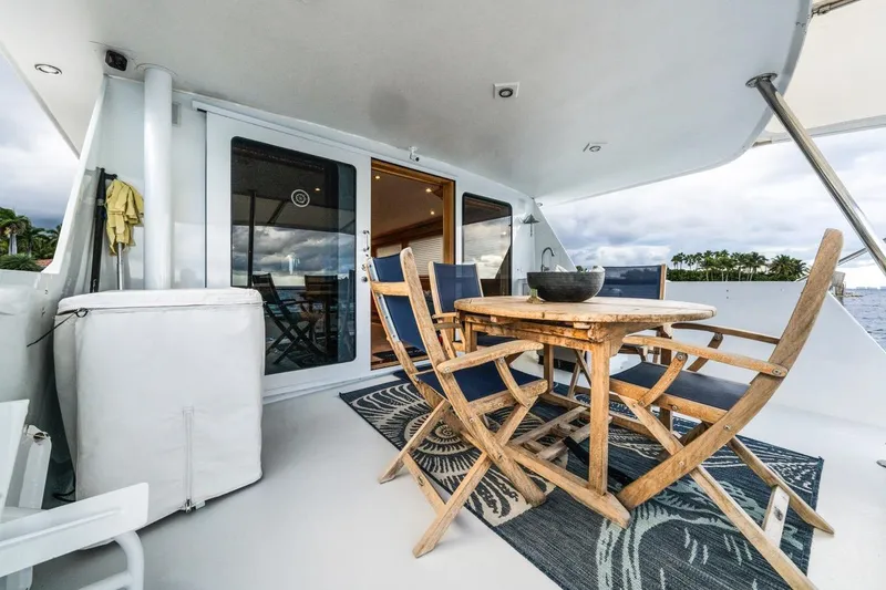 Slide: The Image of Outdoor dining area on 2000 Hatteras 74 Cockpit Motor Yacht, featuring wooden table and chairs. - 24