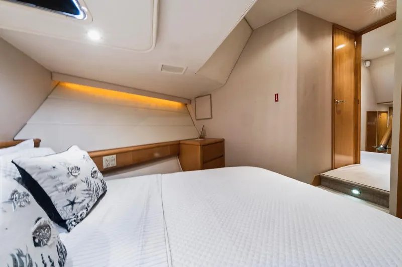 Slide: The Image of Interior cabin of 2000 Hatteras 74 Cockpit Motor Yacht, featuring cozy bed and wooden accents. - 51
