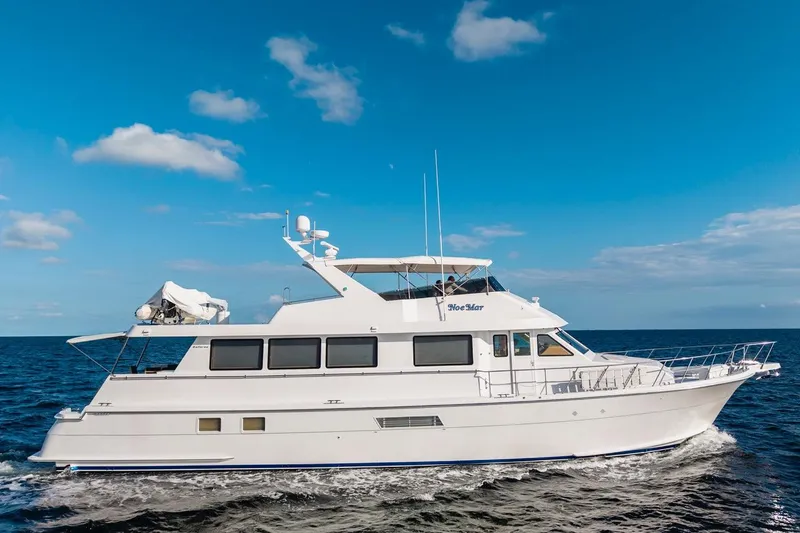Slide: The Image of Hatteras 74 Cockpit Motor Yacht 2000 cruising on open sea under blue sky. - 74