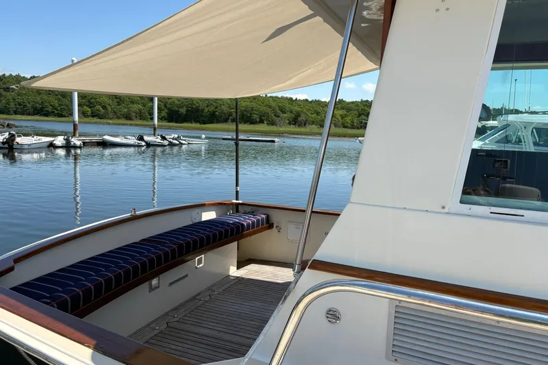Slide: The Image of 2004 Bruckmann Bluestar 38 yacht with shaded seating area, docked by calm waters. - 49