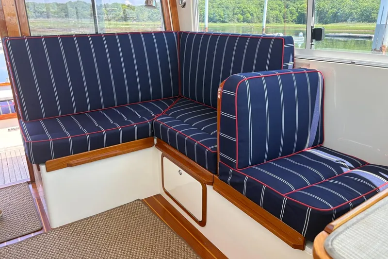 Slide: The Image of Navy-striped seating in 2004 Bruckmann Bluestar 38 boat interior, featuring wooden accents and window view. - 47