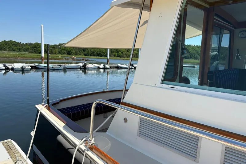 Slide: The Image of 2004 Bruckmann Bluestar 38 yacht docked by serene waters, featuring sleek design and shaded deck. - 55