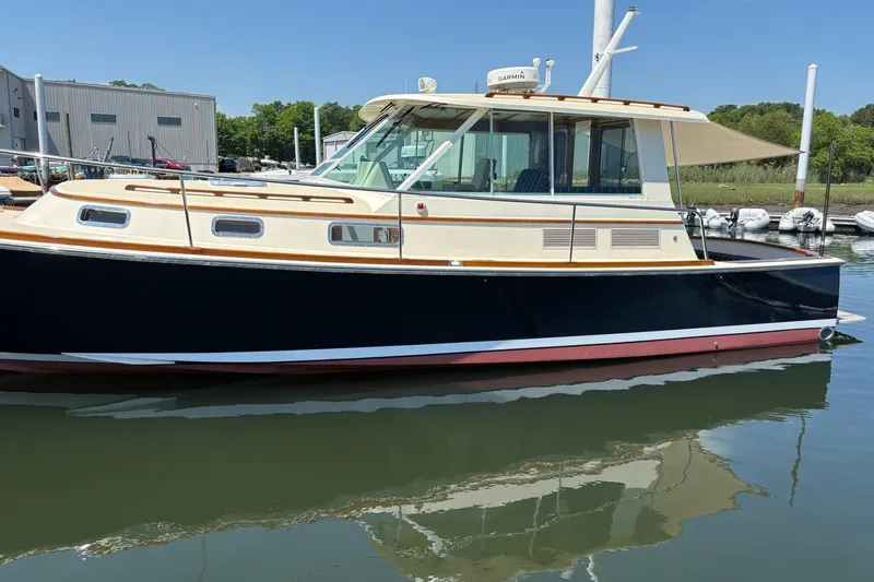 Slide: The Image of 2004 Bruckmann Bluestar 38 boat docked in a marina, reflecting on calm water. - 56