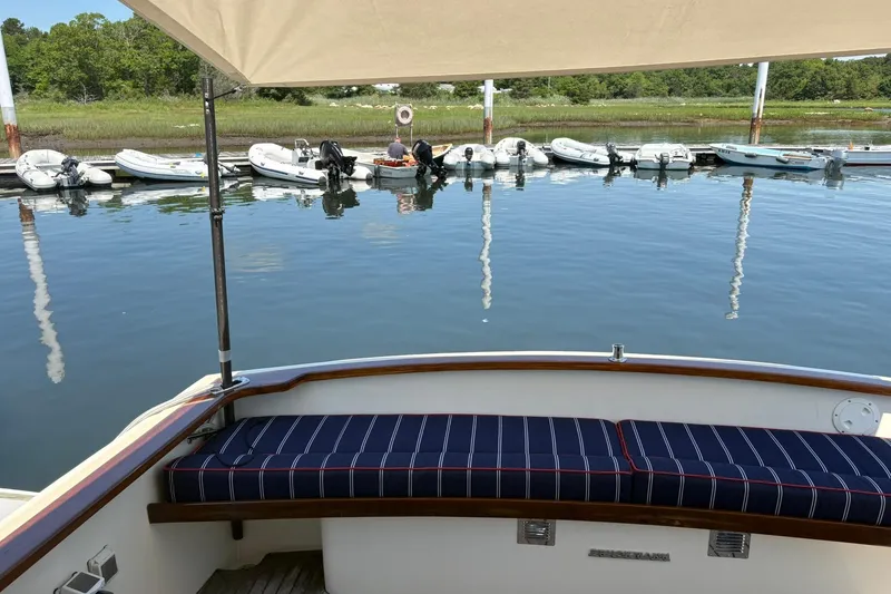 Slide: The Image of 2004 Bruckmann Bluestar 38 yacht with striped seating, docked near small boats. - 46