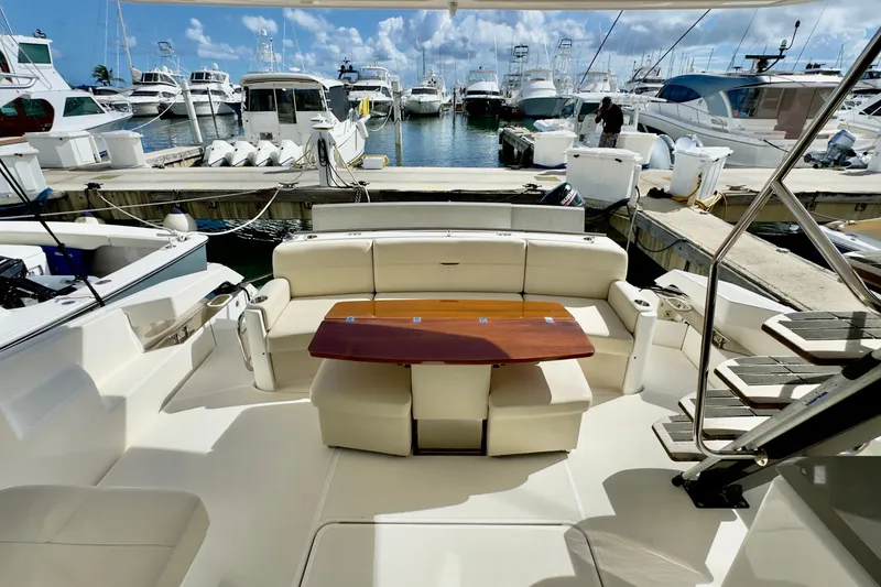 Slide: The Image of 2020 Tiara Yachts F53 Flybridge at marina, featuring elegant seating and wooden table. - 5