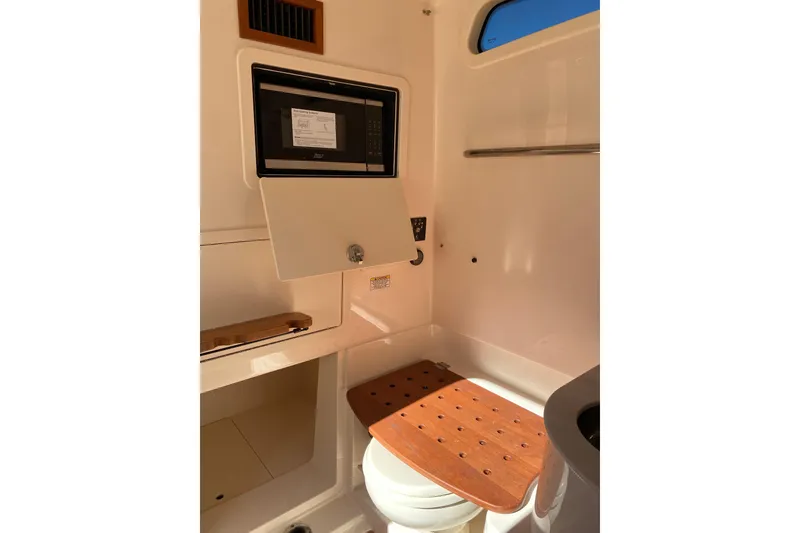 Slide: The Image of 2026 Grady-White Canyon 336 boat interior with wooden seat and storage compartment. - 10