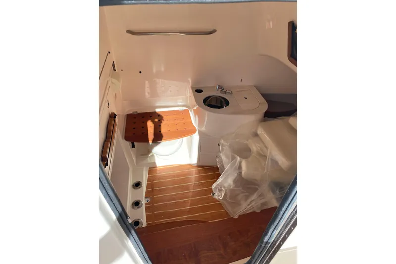 Slide: The Image of 2026 Grady-White Canyon 336 boat interior with wooden flooring and compact bathroom amenities. - 8