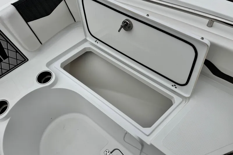 Slide: The Image of 2022 Wellcraft 222 Scarab Offshore boat storage compartment with open lid and cup holders. - 14