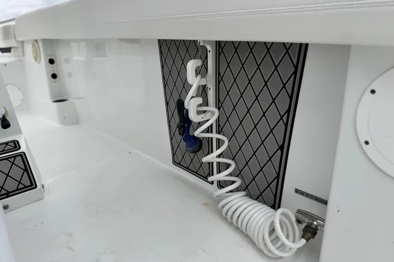 Slide: The Image of 2022 Wellcraft 222 Scarab Offshore boat interior with coiled hose and storage compartment. - 25