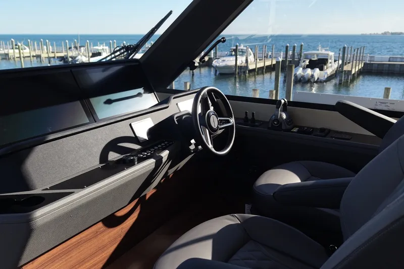 Slide: The Image of Steuerstand einer modernen Yacht mit grauen Sitzen und Blick auf den Hafen. - 15