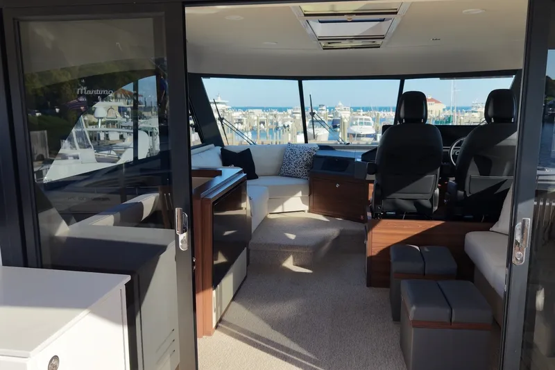 Slide: The Image of Innenraum einer modernen Yacht mit eleganten Sitzen und Panoramafenstern, die einen Hafen überblicken. - 13