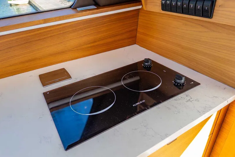 Slide: The Image of Modern kitchen cooktop on 2020 Coastal Craft 33 Express yacht, featuring sleek design and wood accents. - 19
