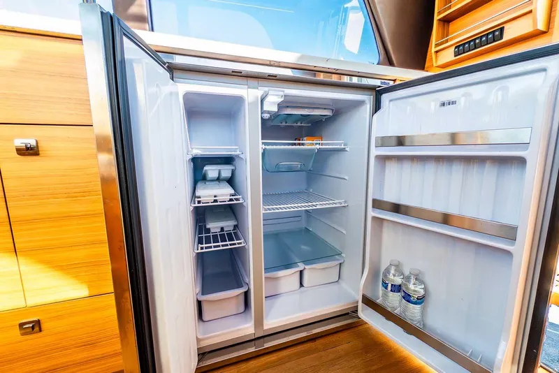 Slide: The Image of Open refrigerator inside 2020 Coastal Craft 33 Express yacht, showcasing spacious interior and storage. - 20