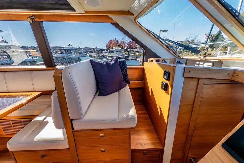 Slide: The Image of 2020 Coastal Craft 33 Express interior with white seating, wooden accents, and marina view. - 22