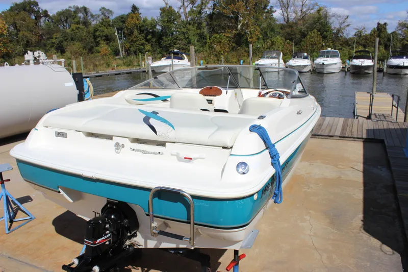 Slide: The Image of 2000 Wellcraft 186 SS/S boat docked, featuring white and teal design, with outboard motor. - 6