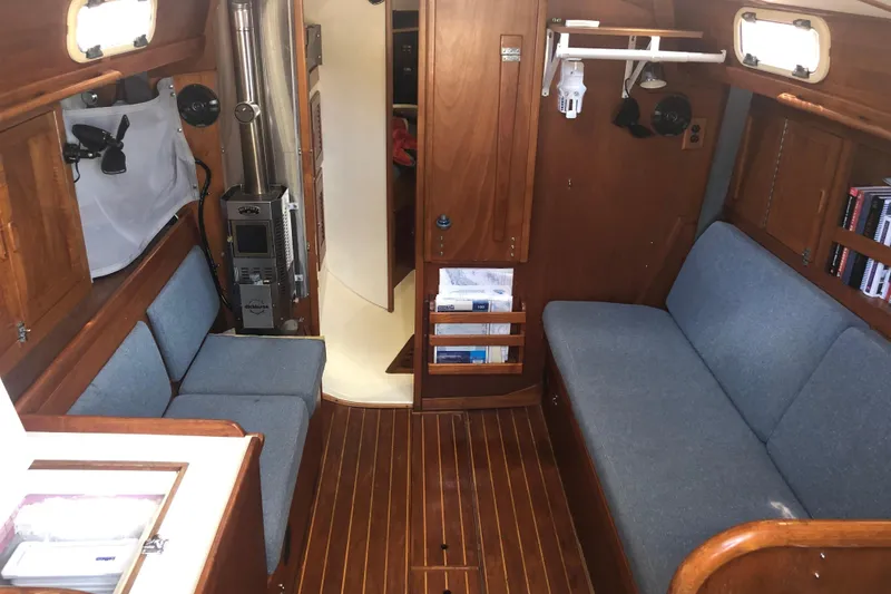 Slide: The Image of 1982 Tartan 33 yacht interior with wood paneling, blue seating, and a compact stove. - 15