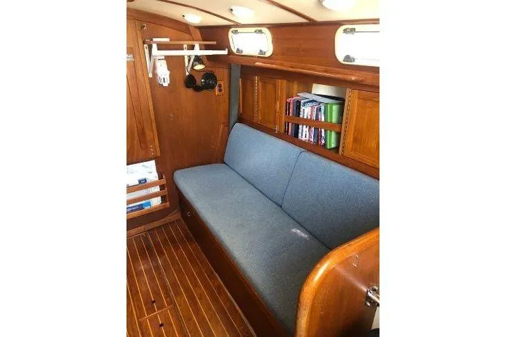 Slide: The Image of 1982 Tartan 33 sailboat interior with wooden finish, blue cushioned seating, and bookshelf. - 17