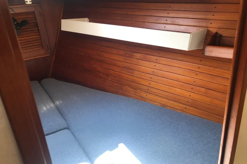 Slide: The Image of 1982 Tartan 33 sailboat interior with wooden paneling and blue cushions. - 19